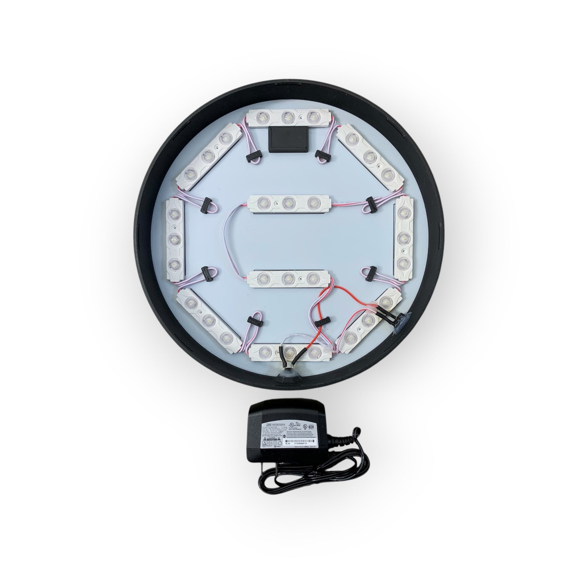 Circular electronic component with wiring and a power adapter on a white background