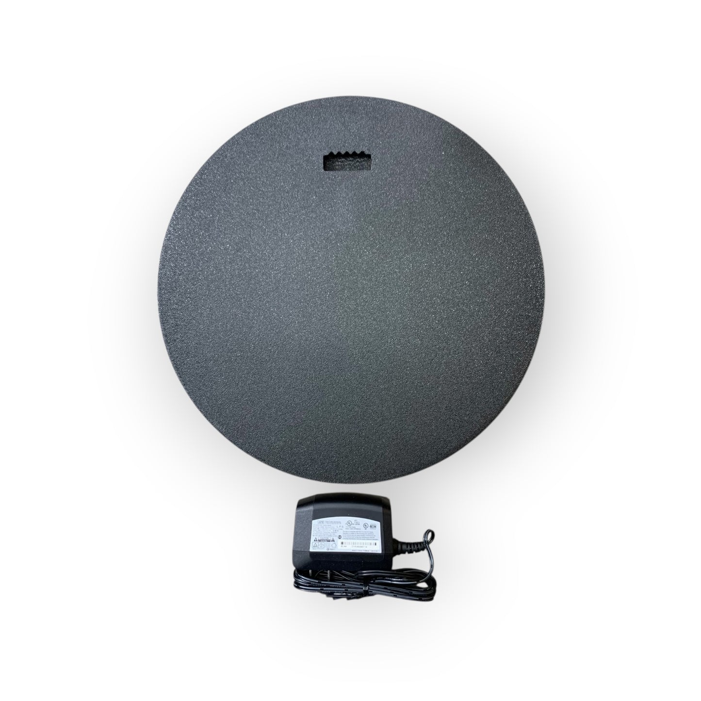 Round black mat with a power adapter on a white background