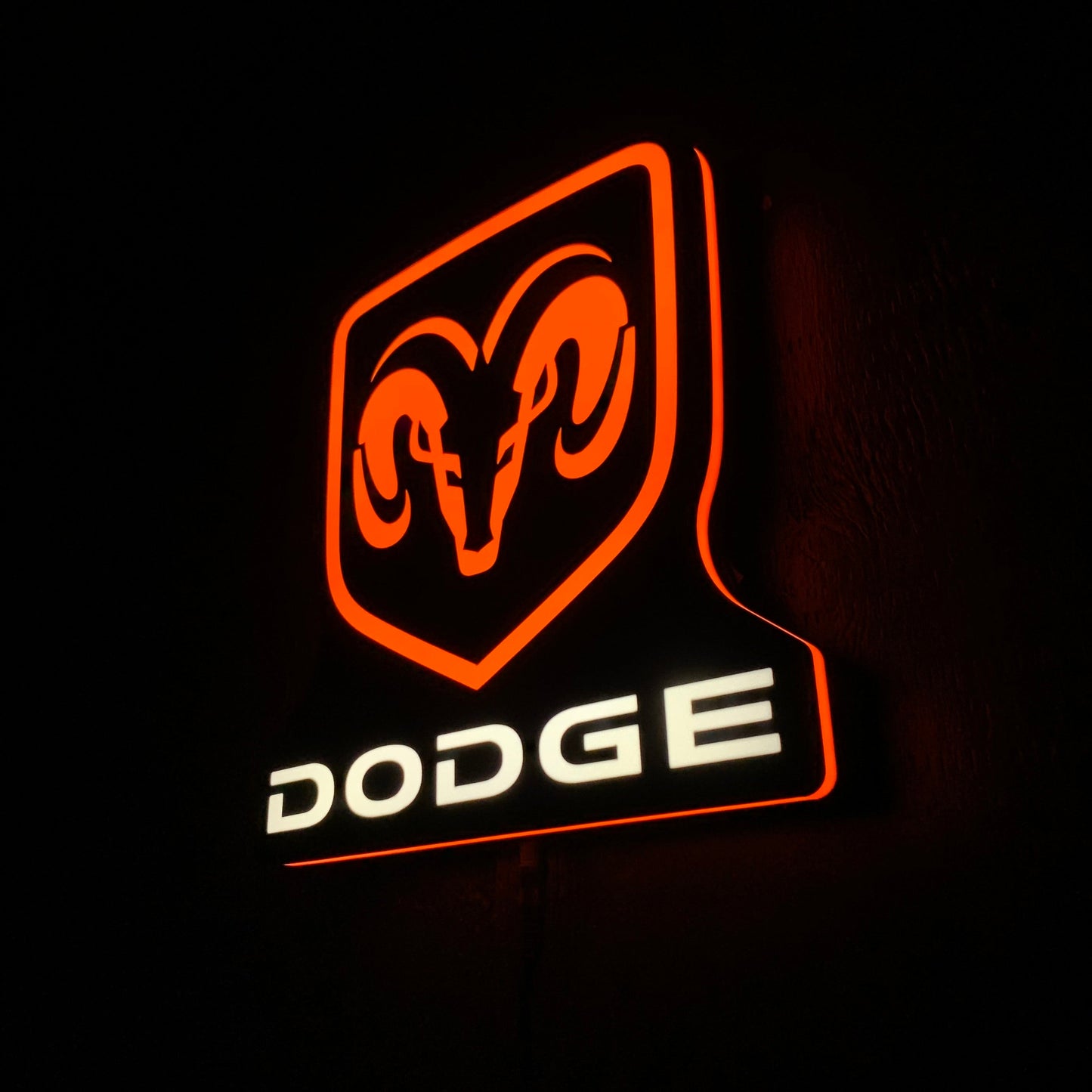 Dodge led indoor sign with illuminated orange and white design on a black background