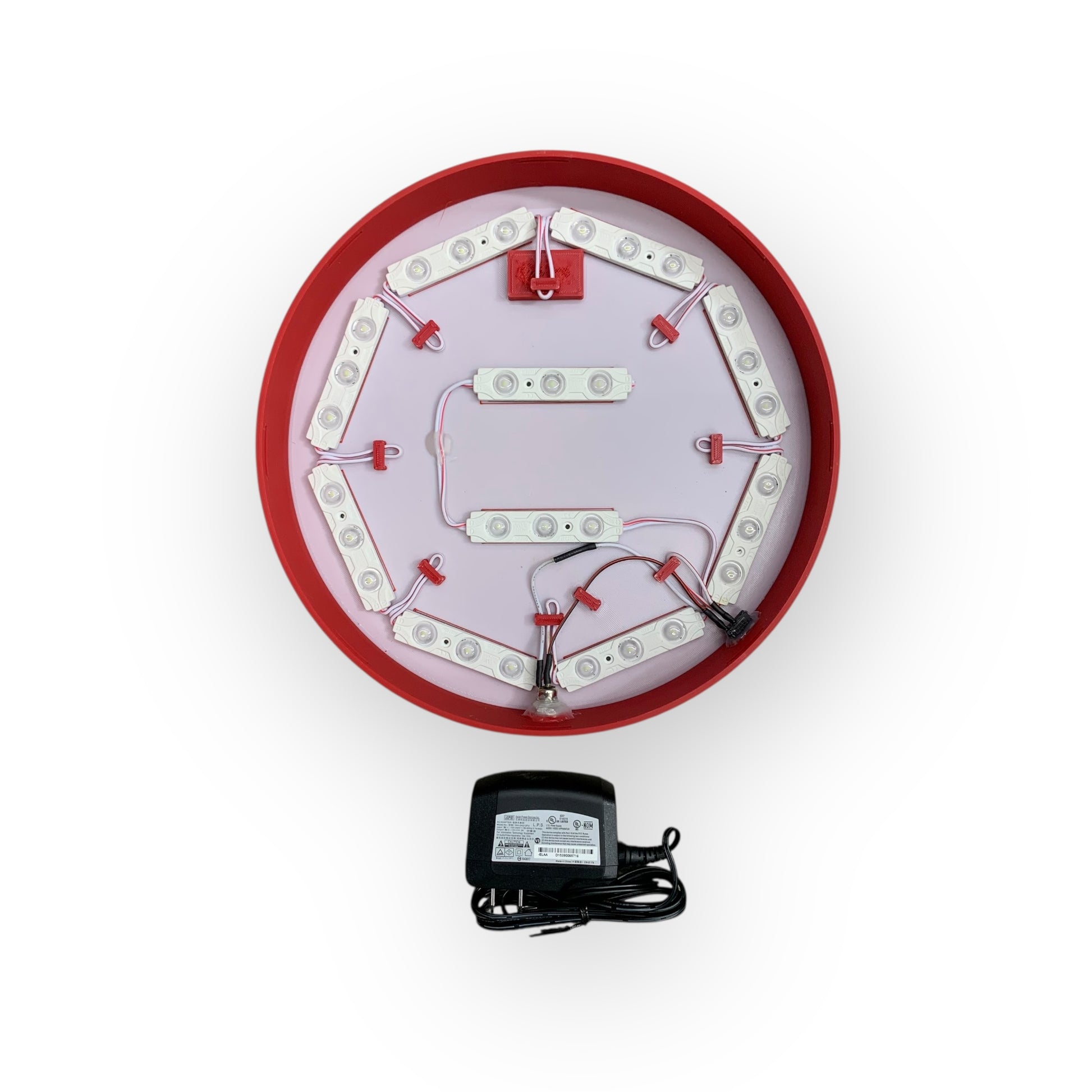 Circular LED light fixture with wiring and a power adapter on a white background