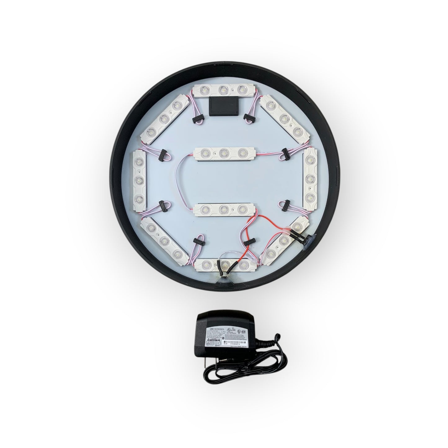 Circular electronic component with wiring and a power adapter on a white background